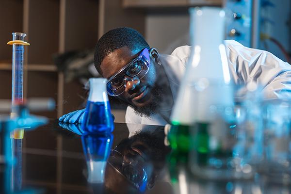 化学系学生正在检查装满蓝色和绿色液体的烧杯